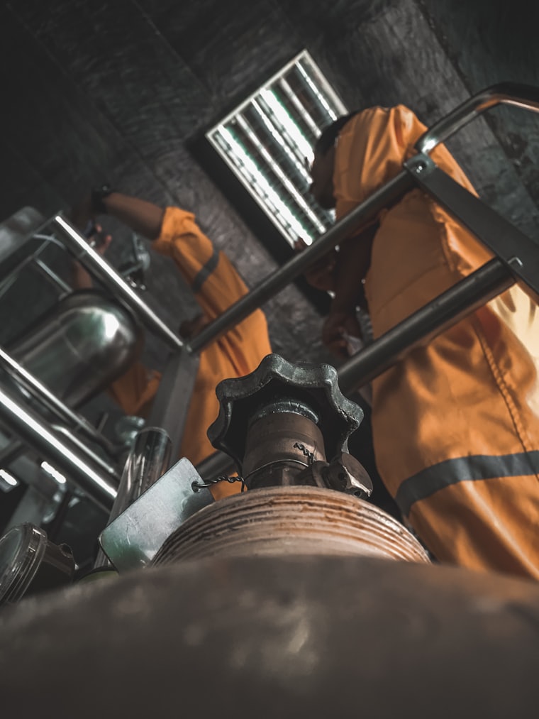 Operarios con overol de seguridad trabajando sobre válvulas en una planta de proceso
